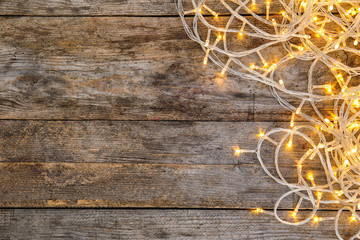 Glowing Christmas lights on wooden background, top view