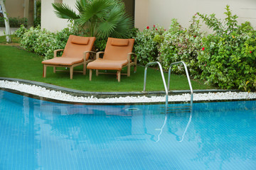 Sunbeds near modern swimming pool with stairs at resort