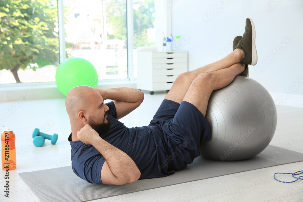 Sticker Overweight man doing exercise with fitness ball in gym