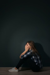 Fototapeta na wymiar Depressed young woman sitting on floor in darkness
