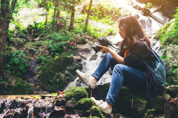 Traveler young woman photographing with camera the waterfall outdoor