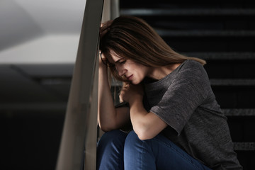 Lonely depressed woman sitting on stairs indoors