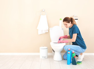 Woman cleaning toilet bowl in bathroom