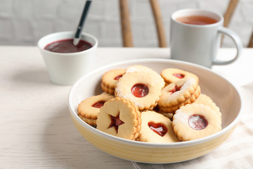 Traditional Christmas Linzer cookies with sweet jam and cup of tea on table