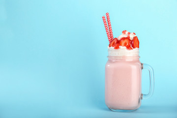 Mason jar with delicious milk shake on color background