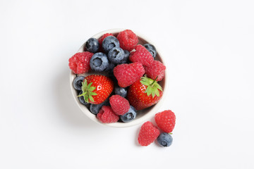 Bowl with raspberries, strawberries and blueberries on white background