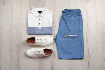 Set of stylish clothes and accessories on wooden floor, flat lay