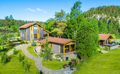Cottage village. Three houses in a green area. Houses surrounded by forest. Cottages are built on the hillside.