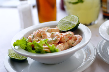 A close up of  a shrimp cocktail dish in a natural light environment with real shrimp and lemon.