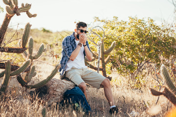 Young man plays the harmonica alone outdoor. Travel lifestyle concept