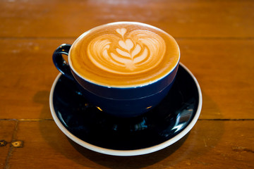 Basic lattte art coffee in a cup on wooden table.