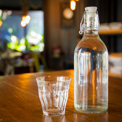 Mineral water in glass bottle left on the wooden table, concept of healthy food and drink.