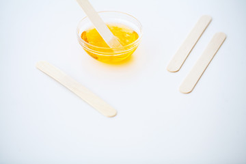 Waxing. Paste for sugaring in beauty salon. Concept depilation with wax and sticks on white background top view.