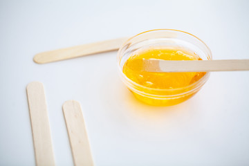 Waxing. Paste for sugaring in beauty salon. Concept depilation with wax and sticks on white background top view.