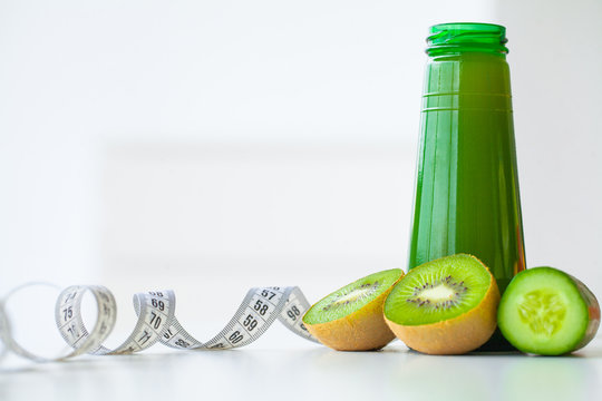 Diet. Fitness and healthy food diet concept, green juice. Fresh fruit, and glass water, measuring tape on white background. Closeup