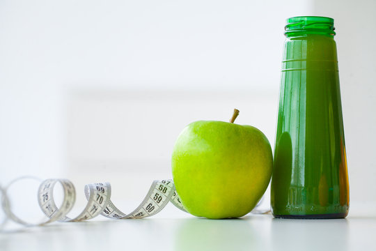 Diet. Fitness and healthy food diet concept, green juice. Fresh fruit, and glass water, measuring tape on white background. Closeup