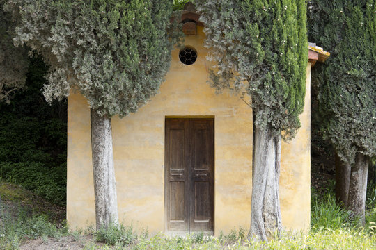 A small Tuscan chapel surrounded by Cypress trees near Lucignano d'Asso, Tuscany