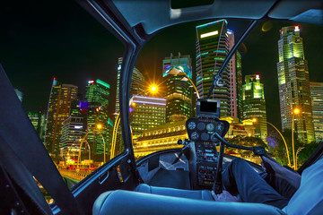 Fototapeta na wymiar Helicopter interior on Singapore financial buildings and skyscrapers of downtown reflected in the sea of the harbor. Scenic flight above Singapore skyline by night in marina bay promenade waterfront.