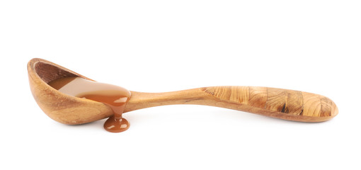 Wooden spoon of caramel sauce isolated
