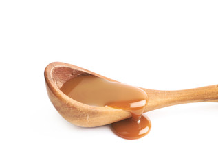 Wooden spoon of caramel sauce isolated