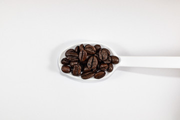 Obraz na płótnie Canvas white spoon with coffee beans . isolated on white background
