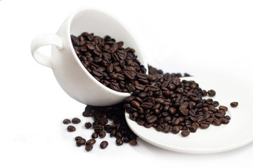 beverage concept of coffee beans heap with white cup and saucer . black and brown color seeds isolated white background . 