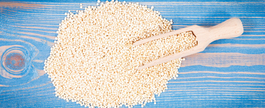 Heap of quinoa seeds and wooden spoon as source healthy minerals and vitamins