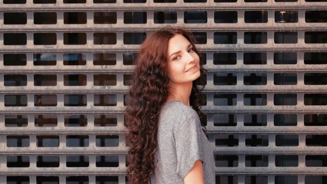 Long haired woman turn back and smile in front of metal grid