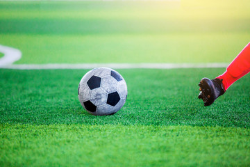 The soccer player shoot ball on artificial turf.