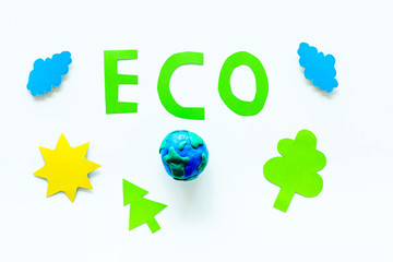 Eco icon cutout near environment symbols as sun, trees, clouds on white background top view
