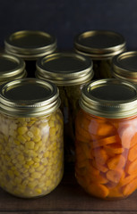 Various Types of Canned Vegetables on a Wooden Table in a Dark Environment