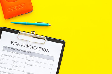 Visa prosessing. Registration of visas. Visa application form and pen on yellow background top view copy space