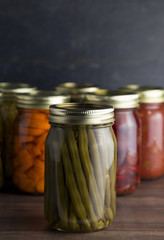 Various Types of Canned Vegetables on a Wooden Table in a Dark Environment