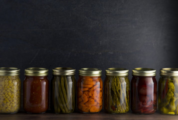 Various Types of Canned Vegetables on a Wooden Table in a Dark Environment