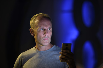 Man using phone while thinking outdoors at night