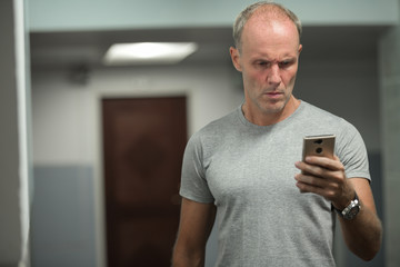 Mature Scandinavian man using phone at hotel