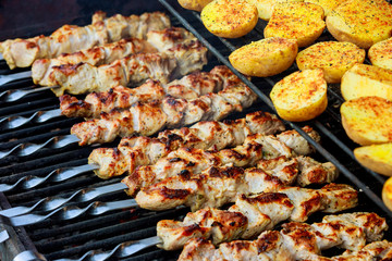 Barbecue skewers with potatoes and meat as well as kebabs are roasted on the grill