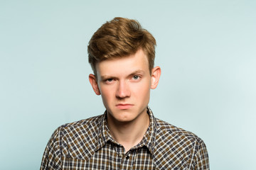 serious man is not impressed by you. critical look with a raised brow. portrait of a young guy on light background. emotion facial expression. feelings and people reaction.