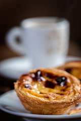 Pasteis de Belem - Pasteis de nata. Typical Portuguese egg custard tart and coffee on wooden background.