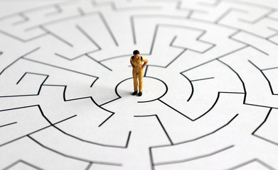 A miniature woman standing in the middle of a maze.