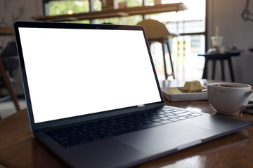 Mockup image of laptop with blank white desktop screen with coffee cup and cake on wooden table in modern cafe