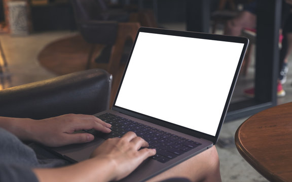 Mockup image of a woman using and typing on laptop with blank white desktop screen while sitting on a chair