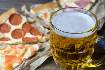 Light beer in glass and fragrant Italian pizza.