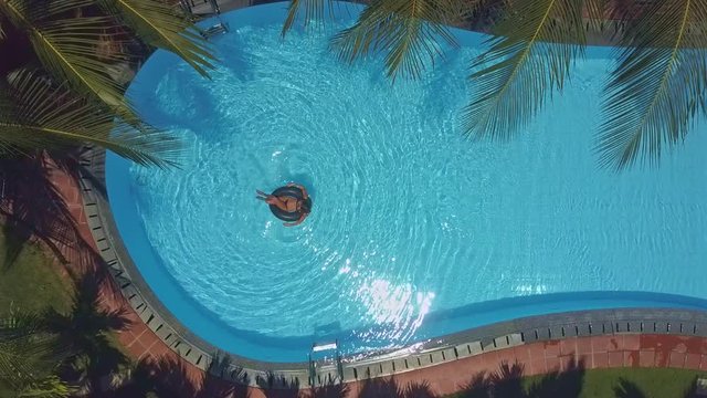 aerial view girl in bikini swims on ring in pool