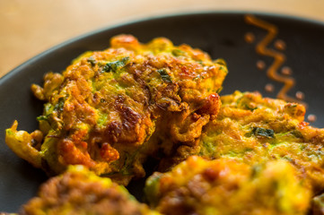 Fried vegetable fritters with zucchini, carrots, herbs, eggs, and cheese.