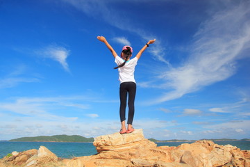 Child girl with arms wide open enjoying the sea,Stand on rock with hand up feel relax or happy or freedom travel,Success and winner concept. 