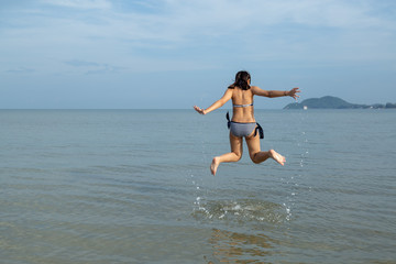 Teenage wearing bikini and jump at the beach.