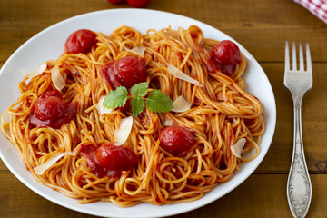 spaghetti with tomato sauce in the dish on the wooden table