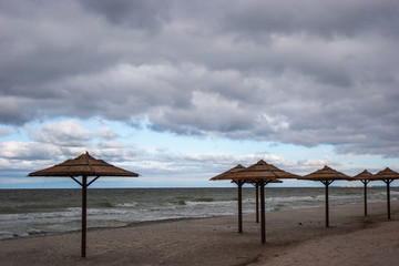 Straw umbrellas from the sun at sea. Cloudy weather and stormy sea.