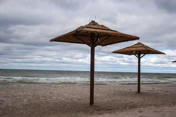 Straw umbrellas from the sun at sea. Cloudy weather and stormy sea.